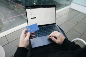 Person gibt einen Rabattcode beim Online-Checkout auf dem Laptop ein